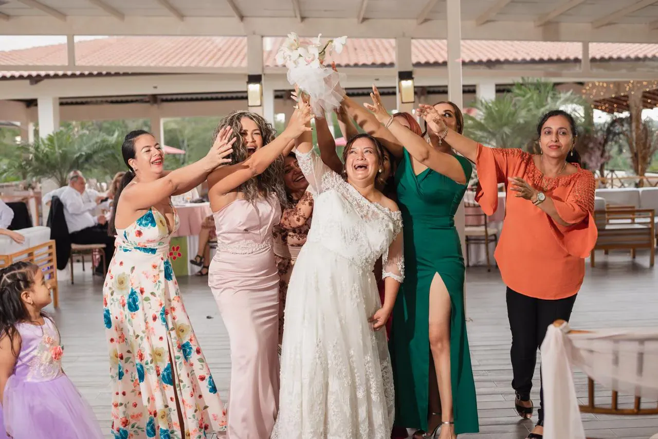 Novia e invitadas alzando las manos hacia el ramo durante la fiesta de boda en Casa Grande Resort
