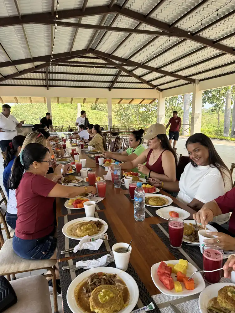 Visitantes compartiendo bolones, fruta y jugo en una mesa larga del comedor de Casa Grande Resort