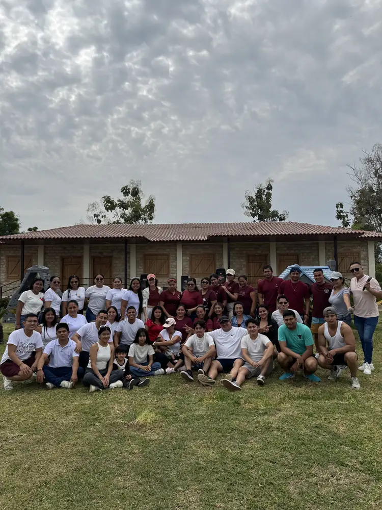 Grupo numeroso de visitantes posando en el césped frente a una edificación de ladrillo de Casa Grande Resort