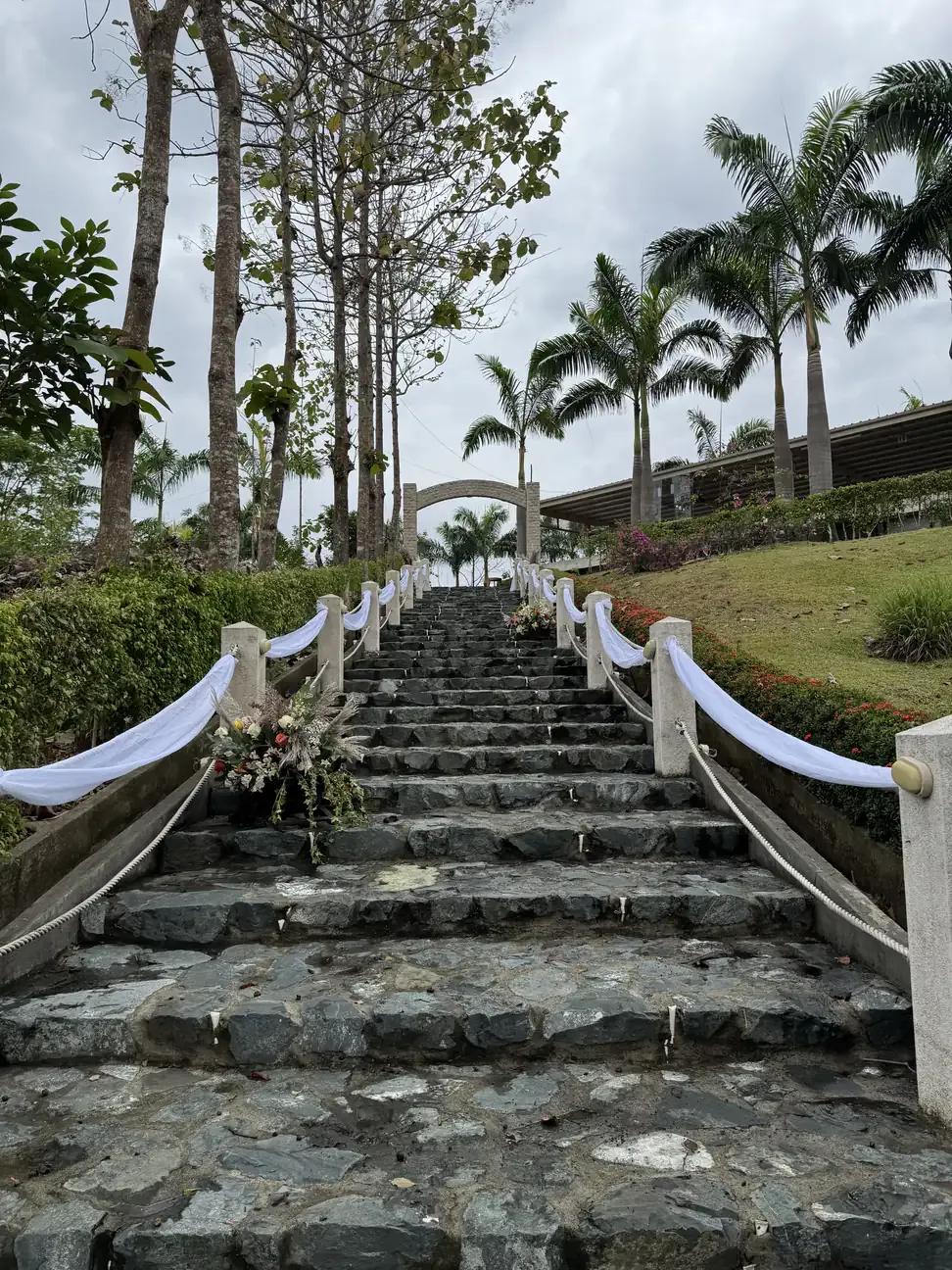 Escalinata de piedra decorada con telas blancas y arreglos florales para una boda en Casa Grande Resort
